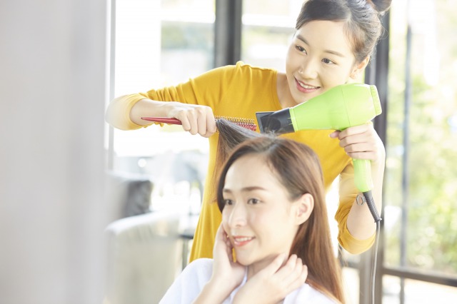お客様の髪をブローする美容師