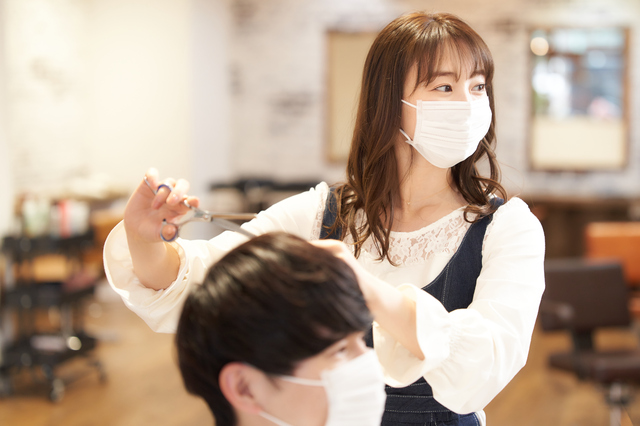 ヘアカットをするマスク着用の美容師とお客