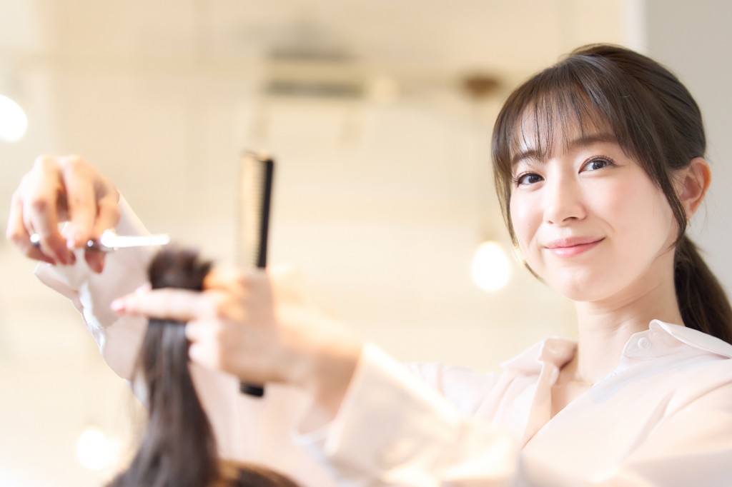 お客の髪を切るヘアスタイリスト